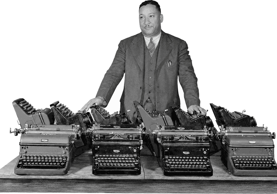 An archive photograph of a clerk standing behind four
typewriters, one hand resting on each of the middle two.