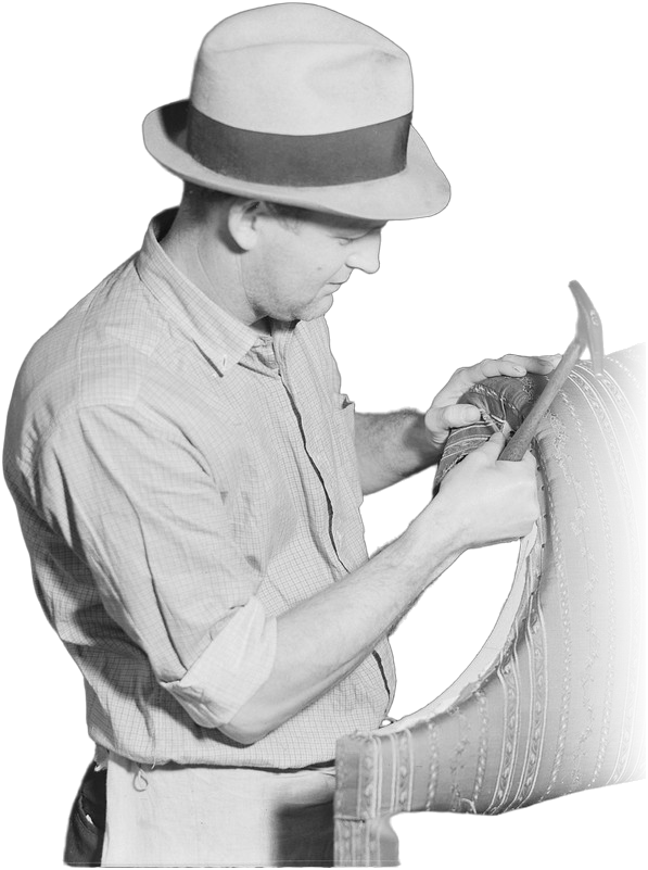 An upholsterer in a felt hat fitting striped fabric to the arm of a sofa.